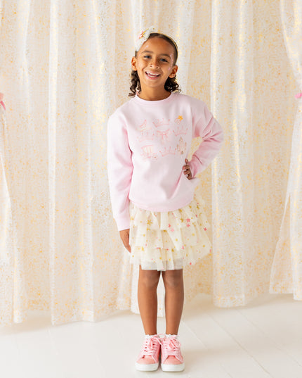 Girl wearing pink sweatshirt and cream tutu with pink and gold stars