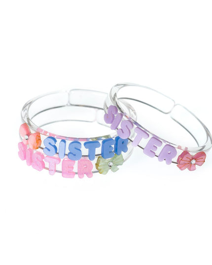 Three clear bangles with pastel letters spelling out sister with bow accents