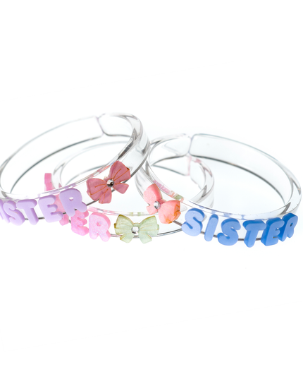 Three clear bangles with pastel letters spelling out sister with bow accents