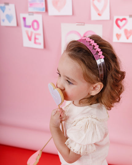 Girl eating a cookie wearing two pink headbands