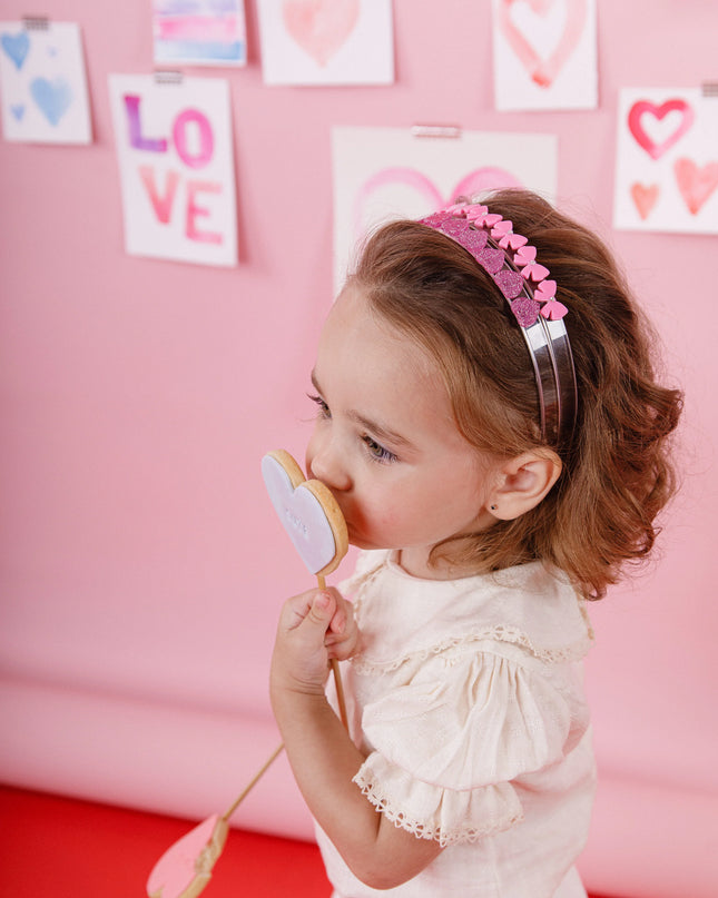 Girl eating a cookie wearing two pink headbands