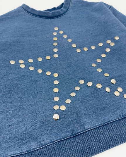 A close-up of a blue denim sweatshirt featuring a large star outline outlined with small metallic silver studs.