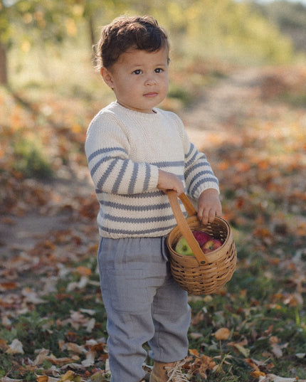 Boy wearing a striped sweater and grey pants