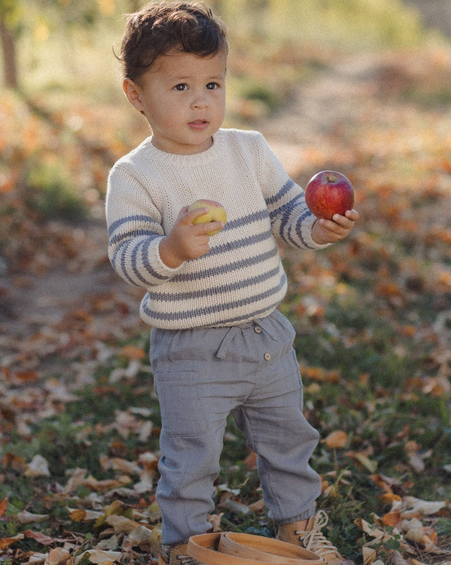 Boy wearing a striped sweater and grey pants