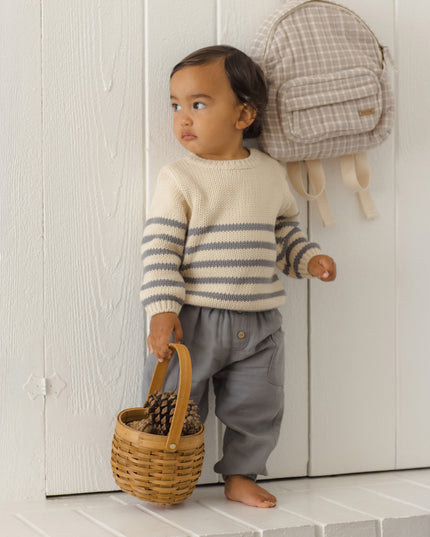 Boy wearing a striped sweater and grey pants