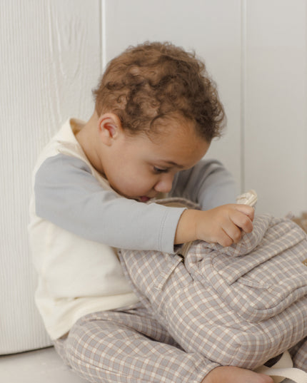 Boy sitting wearing long sleeve children's white raglan tee with grey sleeves and grey plaid pants