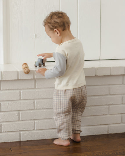 Boy standing, playing wearing long sleeve children's white raglan tee with grey sleeves and grey plaid pants