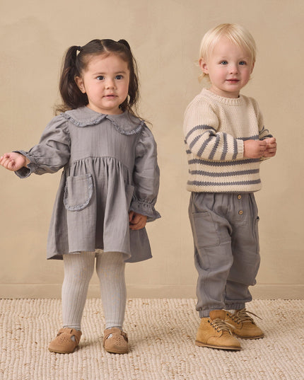 Girl wearing a grey dress and boy wearing a striped sweater and grey pants