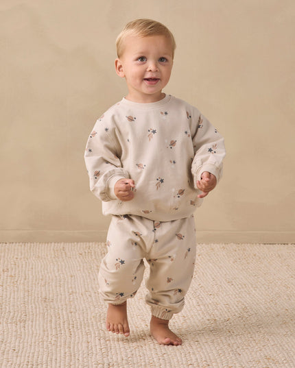 A boy wearing a matching sweatshirt and sweatpants with an all over space print. 