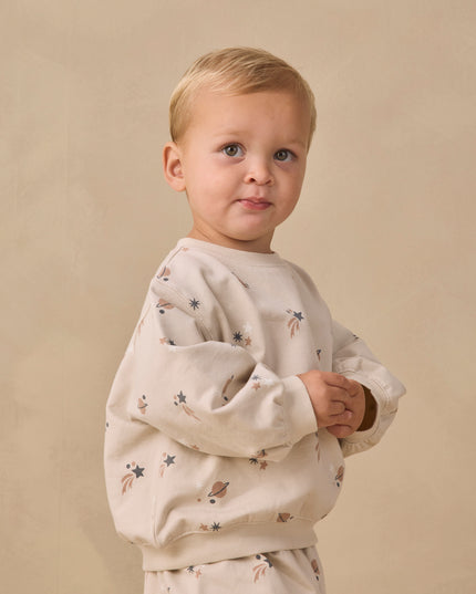 A boy wearing a long sleeve sweatshirt with an all over space print