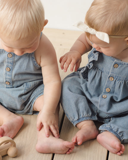 Two babies sitting wearing denim outfits