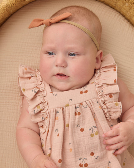 Baby wearing Blush romper with cherry print