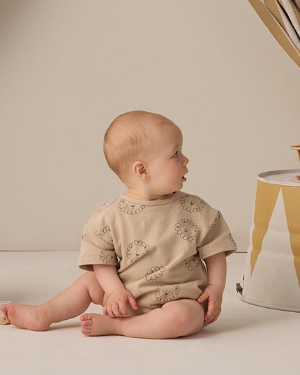 Baby wearing beige romper with lion print