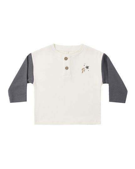 A kid's long-sleeve henley shirt with an off-white body and dark gray sleeves, featuring a three-button placket and a small shooting star design on the left chest.