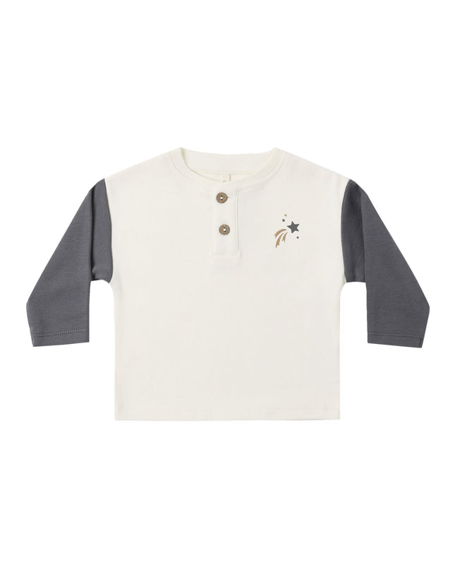 A kid's long-sleeve henley shirt with an off-white body and dark gray sleeves, featuring a three-button placket and a small shooting star design on the left chest.