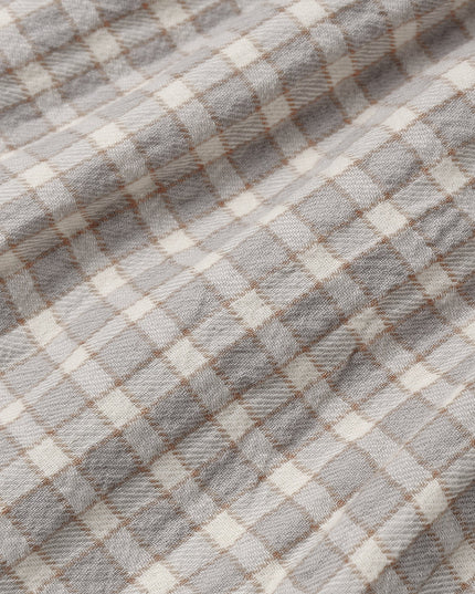 A close-up of a plaid fabric with a gray and off-white checkered pattern and thin brown intersecting lines.