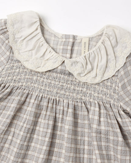 Close up of a girls dress with blue checkered pattern and white collar 