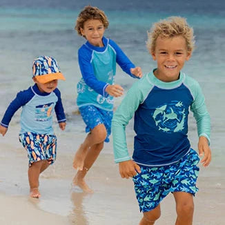 Three children in colorful swimwear running on a beach.