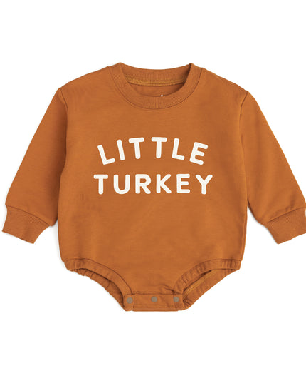 A baby long-sleeve romper in a warm burnt orange color, featuring the text 'LITTLE TURKEY' printed in white capital letters across the chest. The bodysuit has a crew neck, long sleeves with ribbed cuffs, and 3-snap closure.