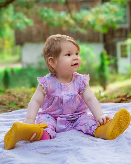 Baby wearing purple bow pattern romper with ruffle sleeves and magnetic closure