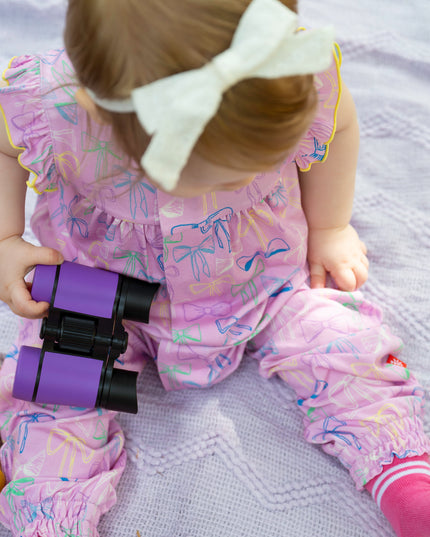 Baby wearing purple bow pattern romper with ruffle sleeves and magnetic closure