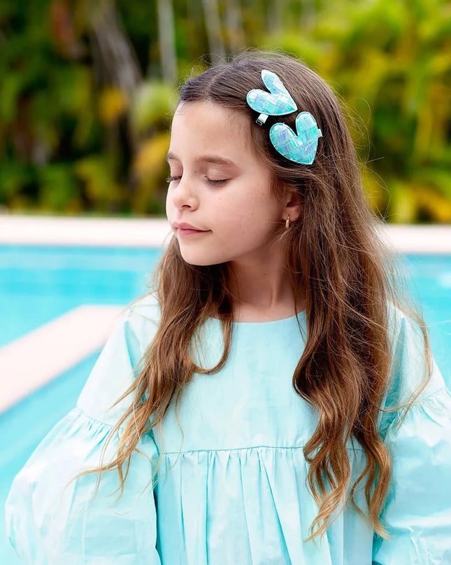 Girl standing by pool wearing turquoise sequin heart hair clips