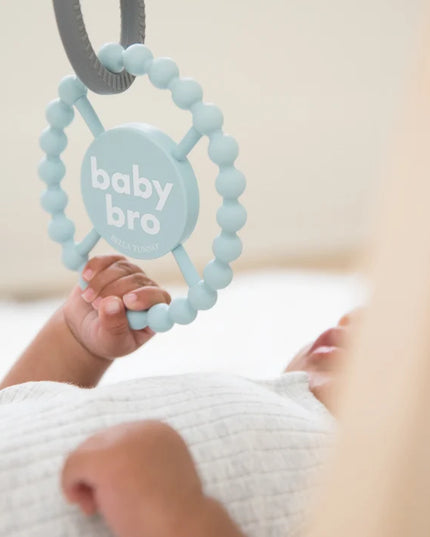 Baby playing with light blue silicone baby teether with the text 'baby bro'
