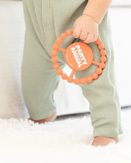 Baby holding orange silicone teething ring with 'party animal text