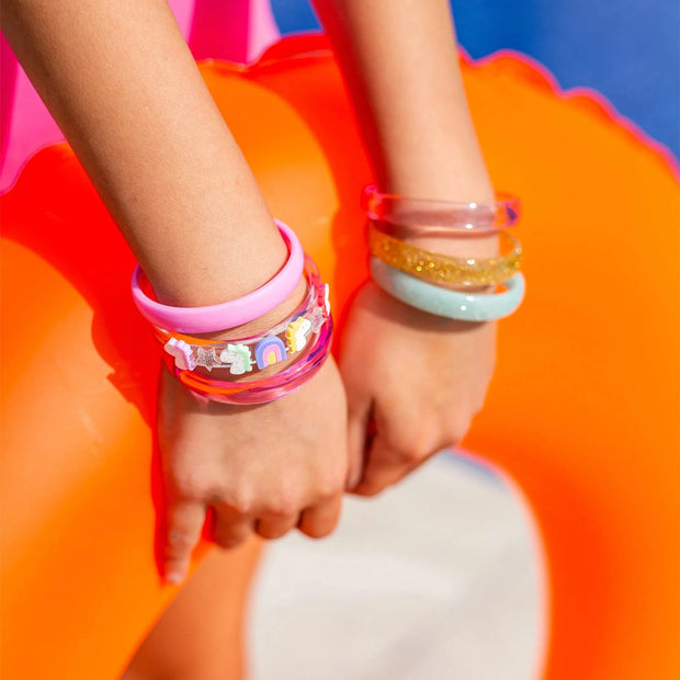 Girl wearing colorful bangles holding an orange swimming toy