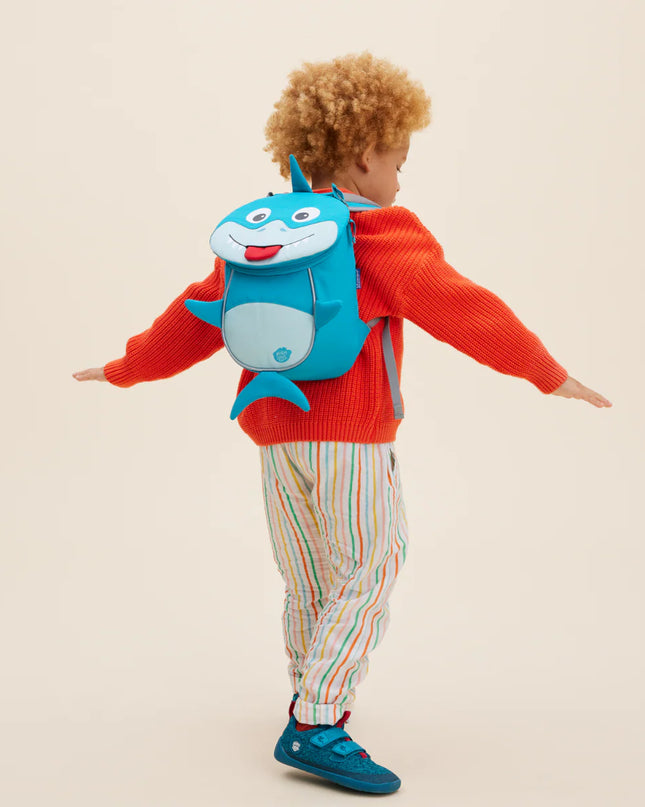 Child wearing a backpack with a shark design