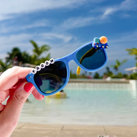 Hand holding vroom truck sunglasses at beach