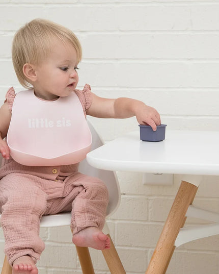 Baby wearing a pink baby bib with 'little sis' text 