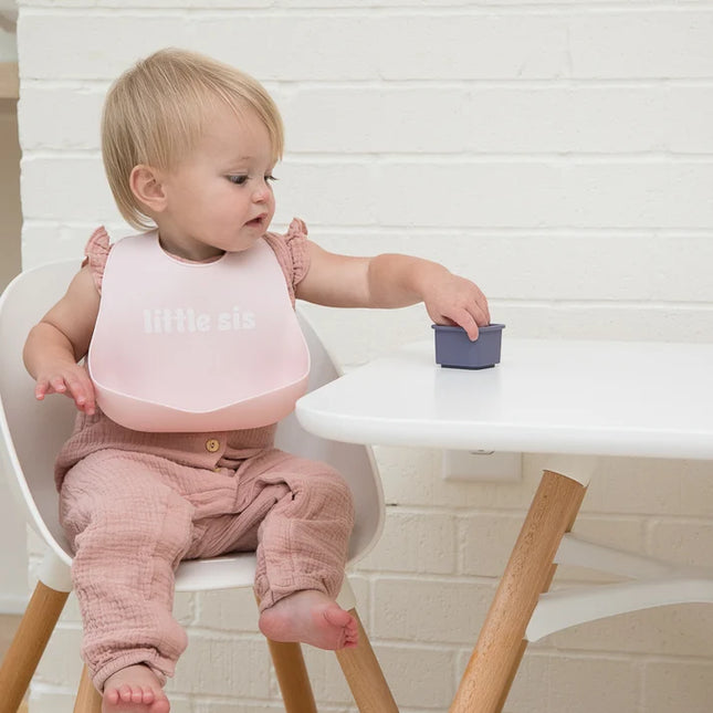 Baby wearing a pink baby bib with 'little sis' text 