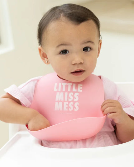 Baby wearing pink bib with 'Little Miss Mess' text 