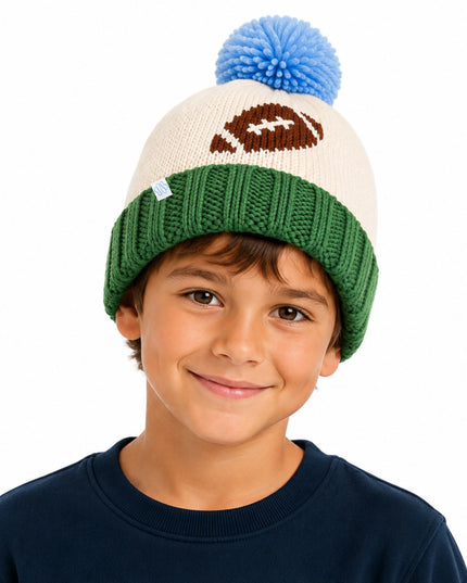 A boy wearing an off-white knit beanie with football, green cuff and blue pom pom