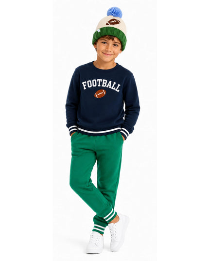 A boy wearing a football sweatshirt and knit pom pom hat