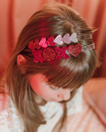 girl wearing headbands with red and pink glitter xoxo design and hearts