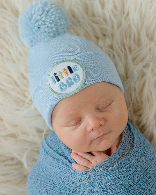 Baby wearing blue 'little bro' hospital beanie with pom pom