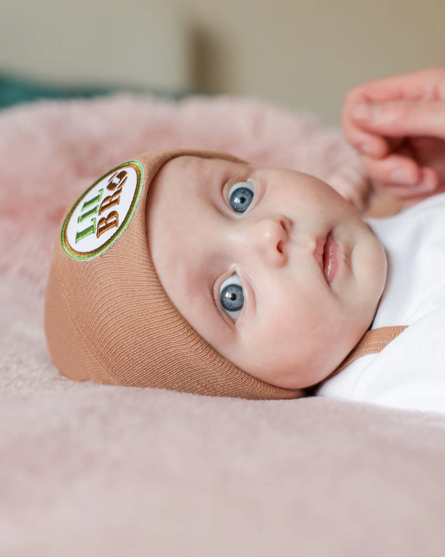 Baby wearing tan hat with lil bro football patch